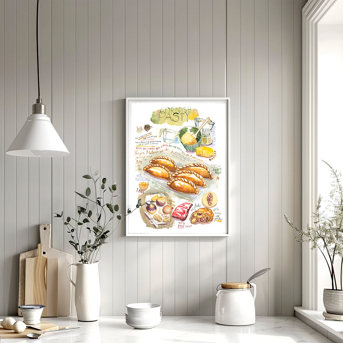 Cornish pasty recipe fine art print in watercolor featuring the ingredients and the finished dish, along with handwritten instructions in English. The framed poster hanging in a Kitchen.