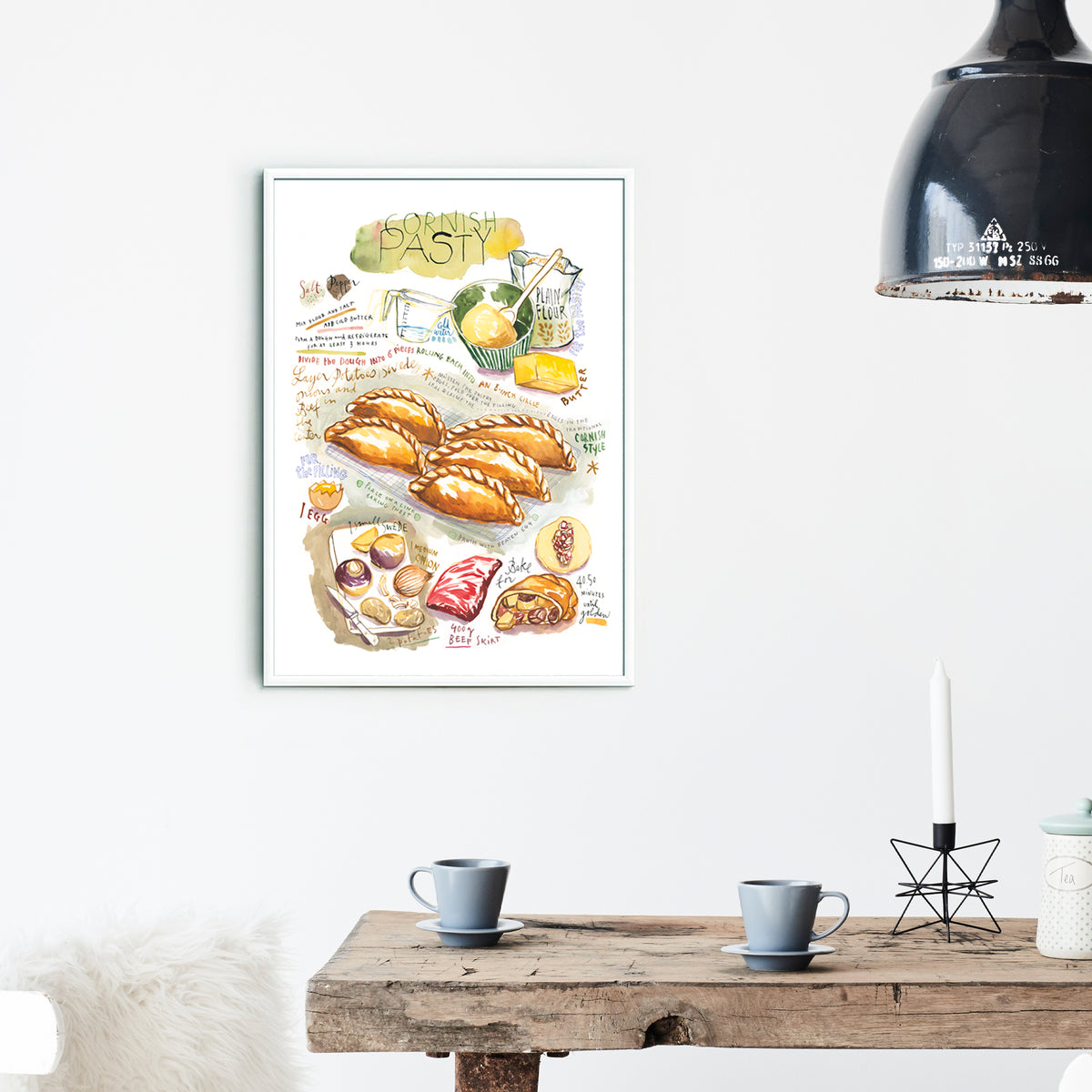 Cornish pasty recipe fine art print in watercolor featuring the ingredients and the finished dish, along with handwritten instructions in English. The framed poster hanging in a dining space.