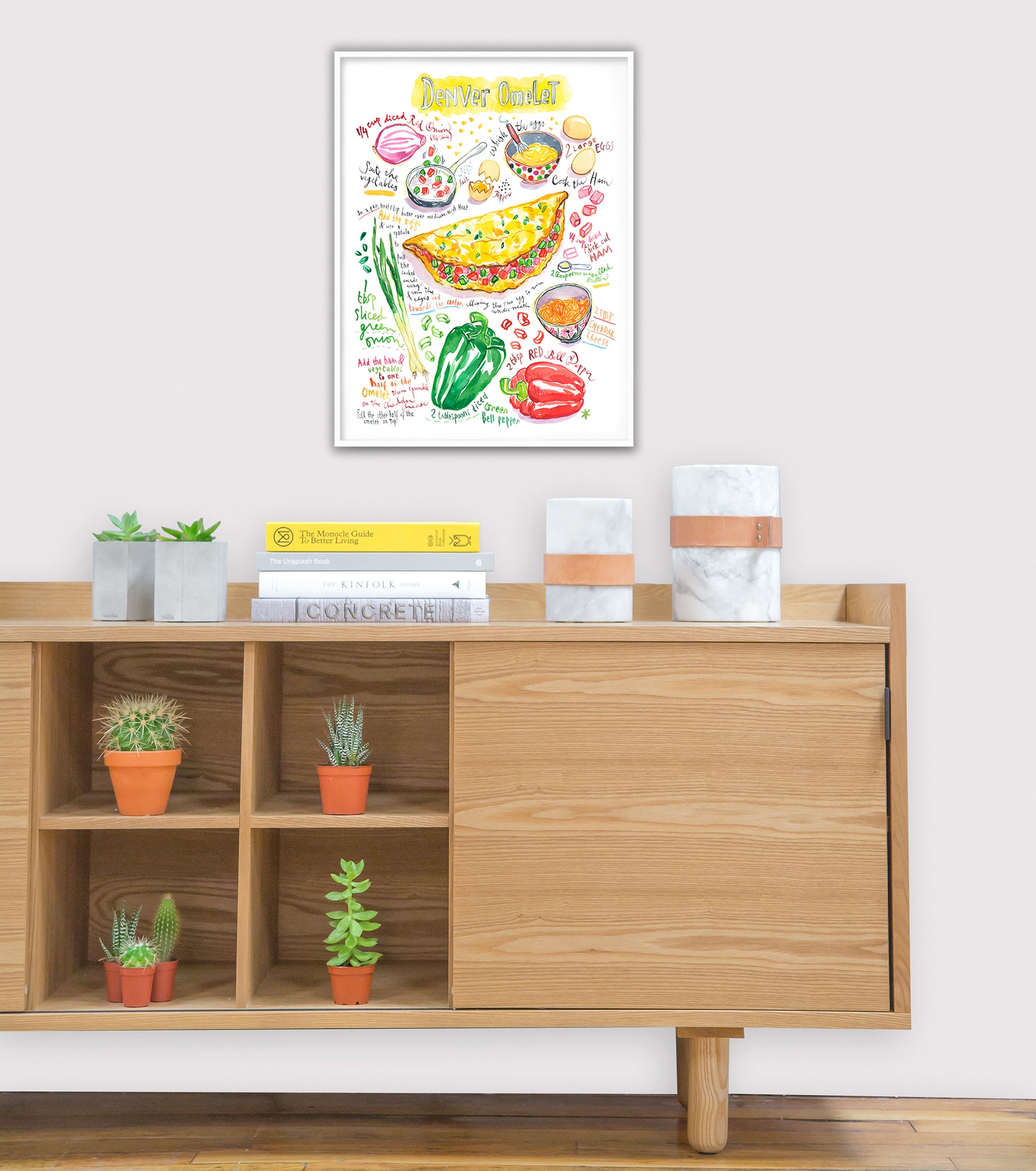 Denver omelet recipe fine art print in watercolor featuring the ingredients and the finished dish, along with handwritten instructions in English. The framed poster hanging in a dining space.
