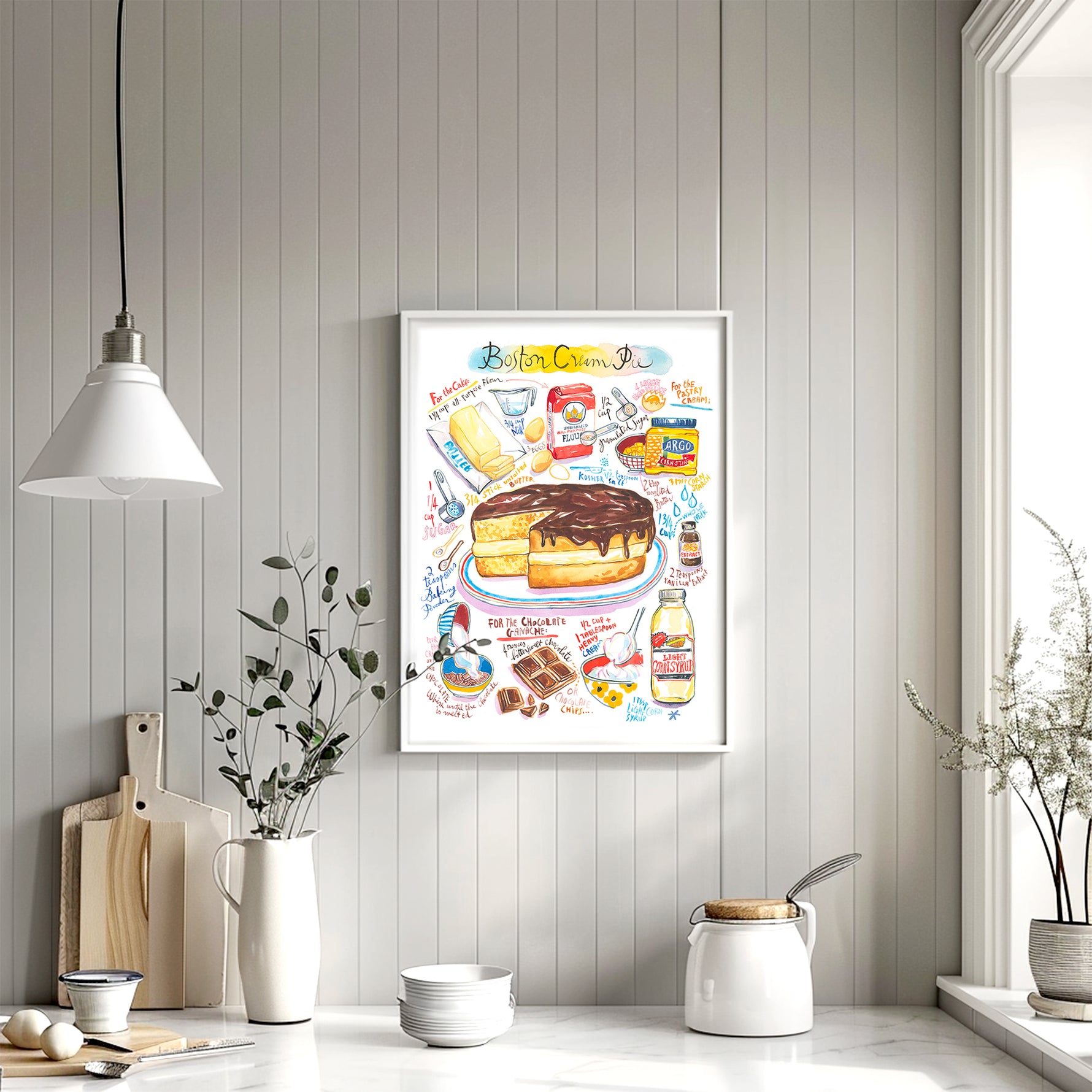Boston cream pie recipe fine art print in watercolor featuring the ingredients and the finished cake, along with handwritten instructions in English. The framed poster hanging in a kitchen space.