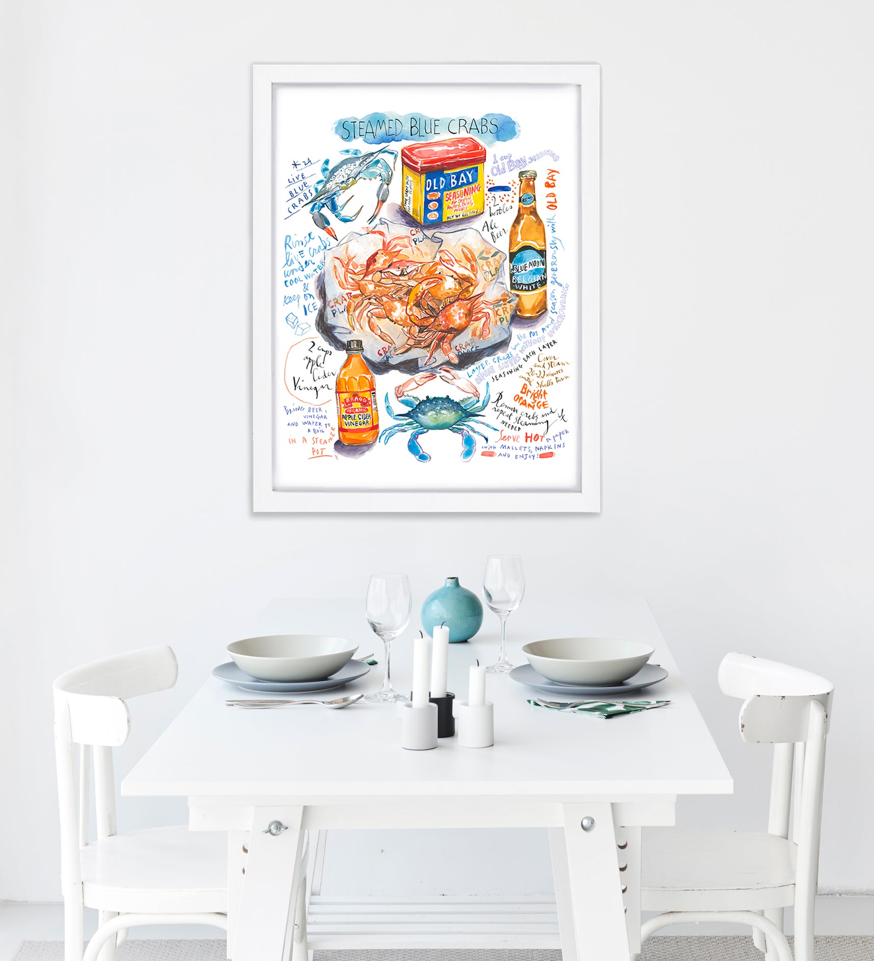 steamed blue crab recipe fine art print in watercolor featuring the ingredients and the finished dish, along with handwritten instructions in English. The framed poster hanging in a dining space.