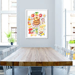 an apple cider donut recipe fine art print in watercolor featuring the ingredients and the finished dessert, along with handwritten instructions in English. The framed poster hanging in a dining space.