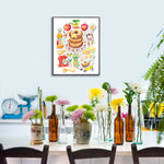 an apple cider donut recipe fine art print in watercolor featuring the ingredients and the finished dessert, along with handwritten instructions in English. The framed poster hanging in a dining space.