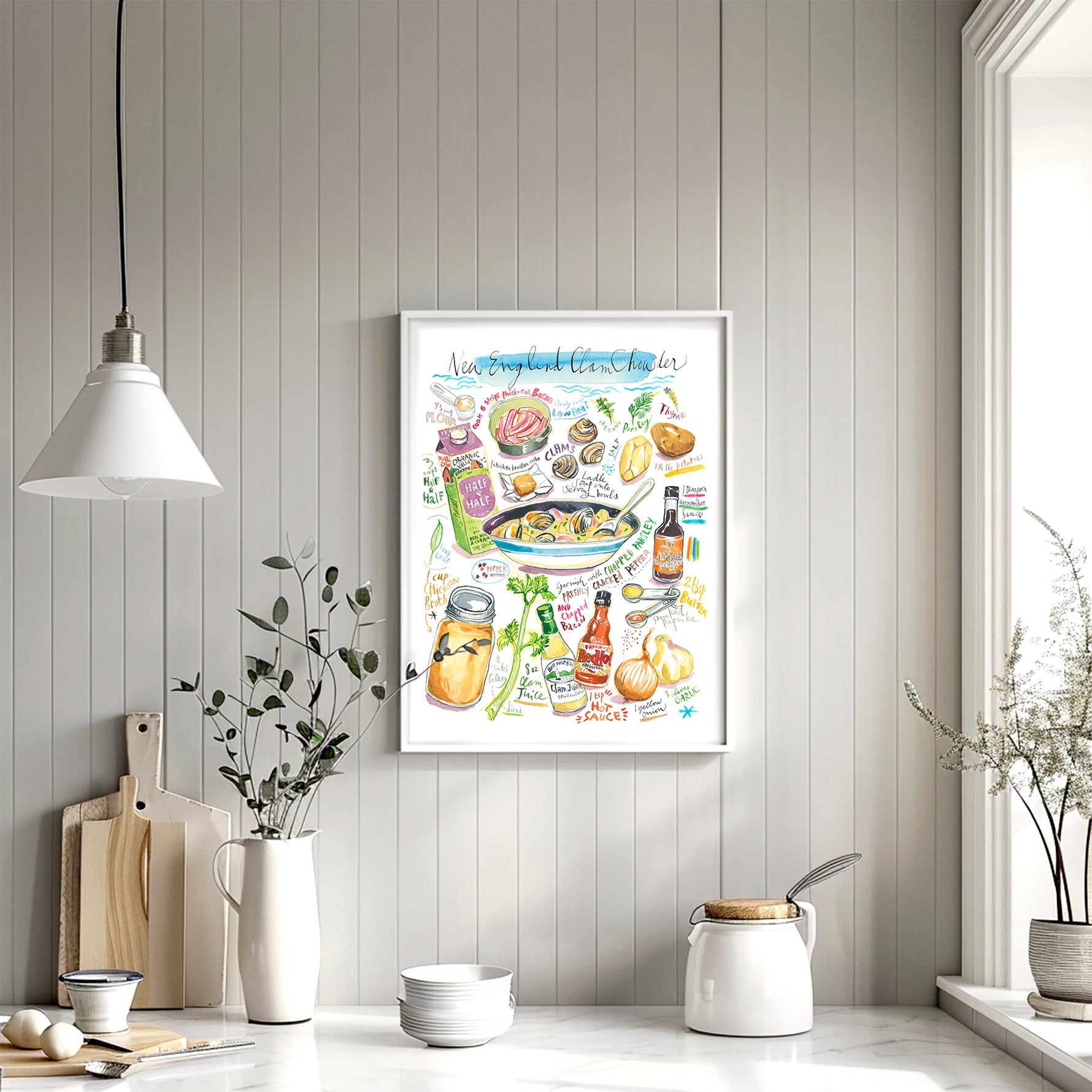 New England clam chowder recipe fine art print in watercolor featuring the ingredients and the finished dish, along with handwritten instructions in English. The framed poster hanging in a kitchen space.