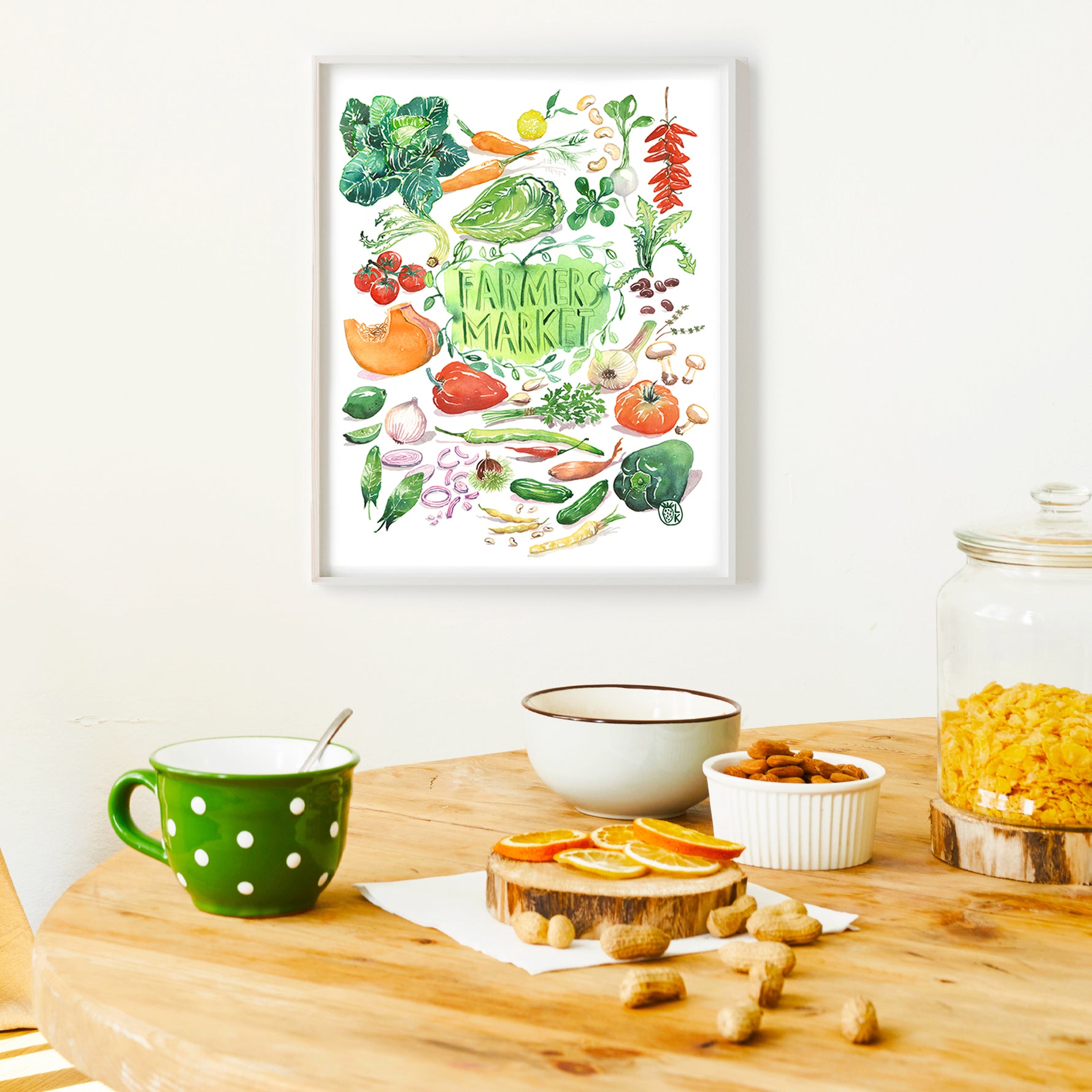 hand painted watercolor print featuring many fresh vegetables and " Framers Market " is hand written in the center of the painting. The print is framed in a dining space