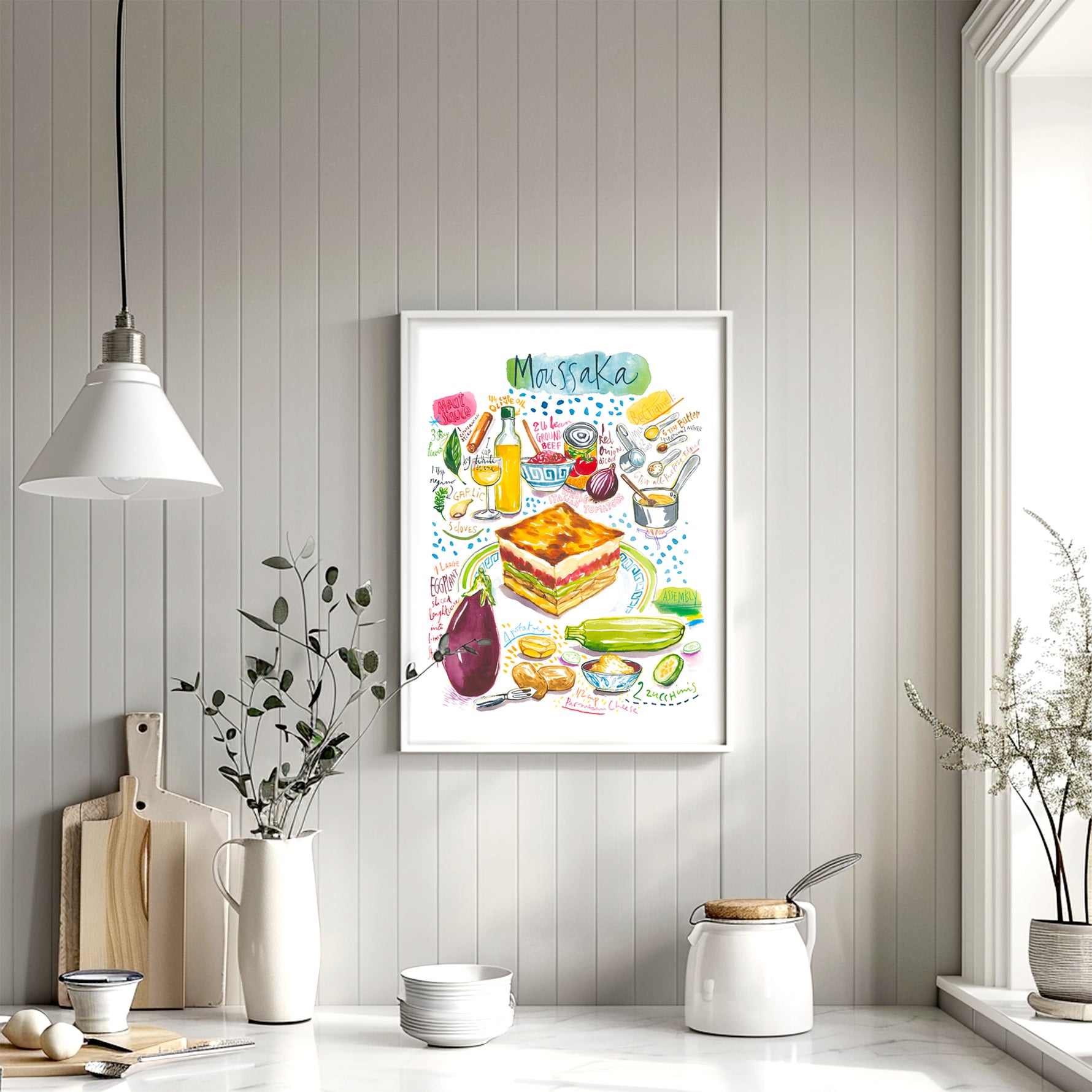 moussaka recipe fine art print in watercolor featuring the ingredients and the finished dish, along with handwritten instructions in English. The framed poster hanging in a dining space.