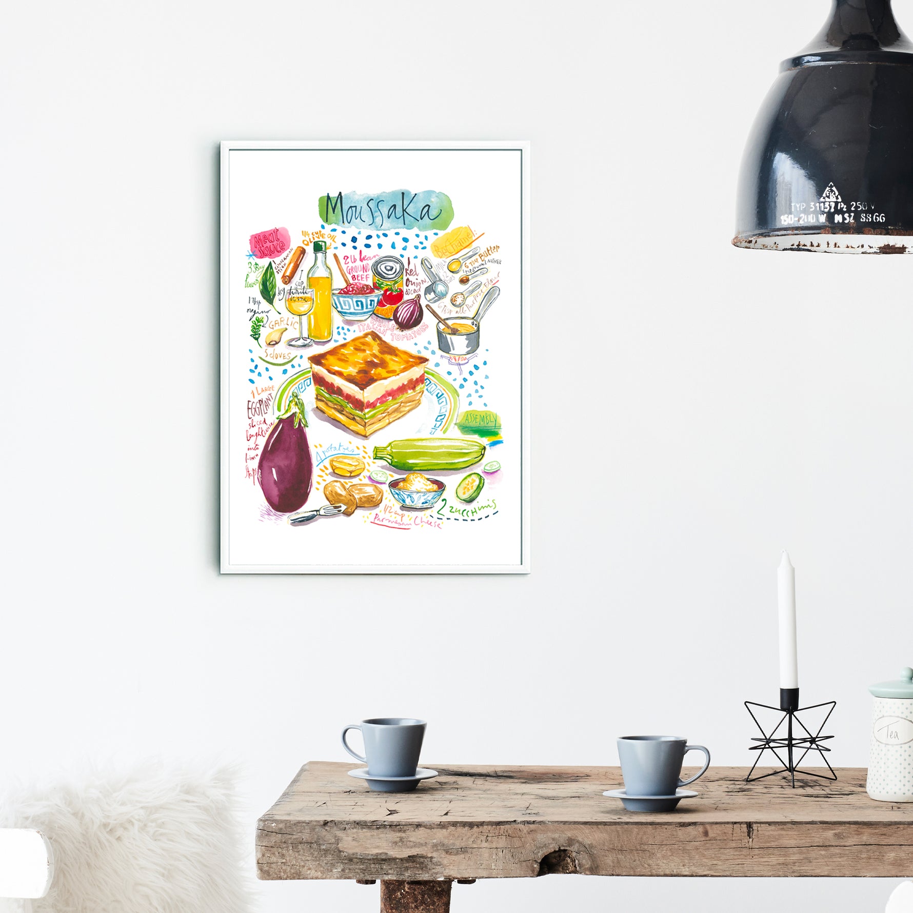 moussaka recipe fine art print in watercolor featuring the ingredients and the finished dish, along with handwritten instructions in English. The framed poster hanging in a dining space.