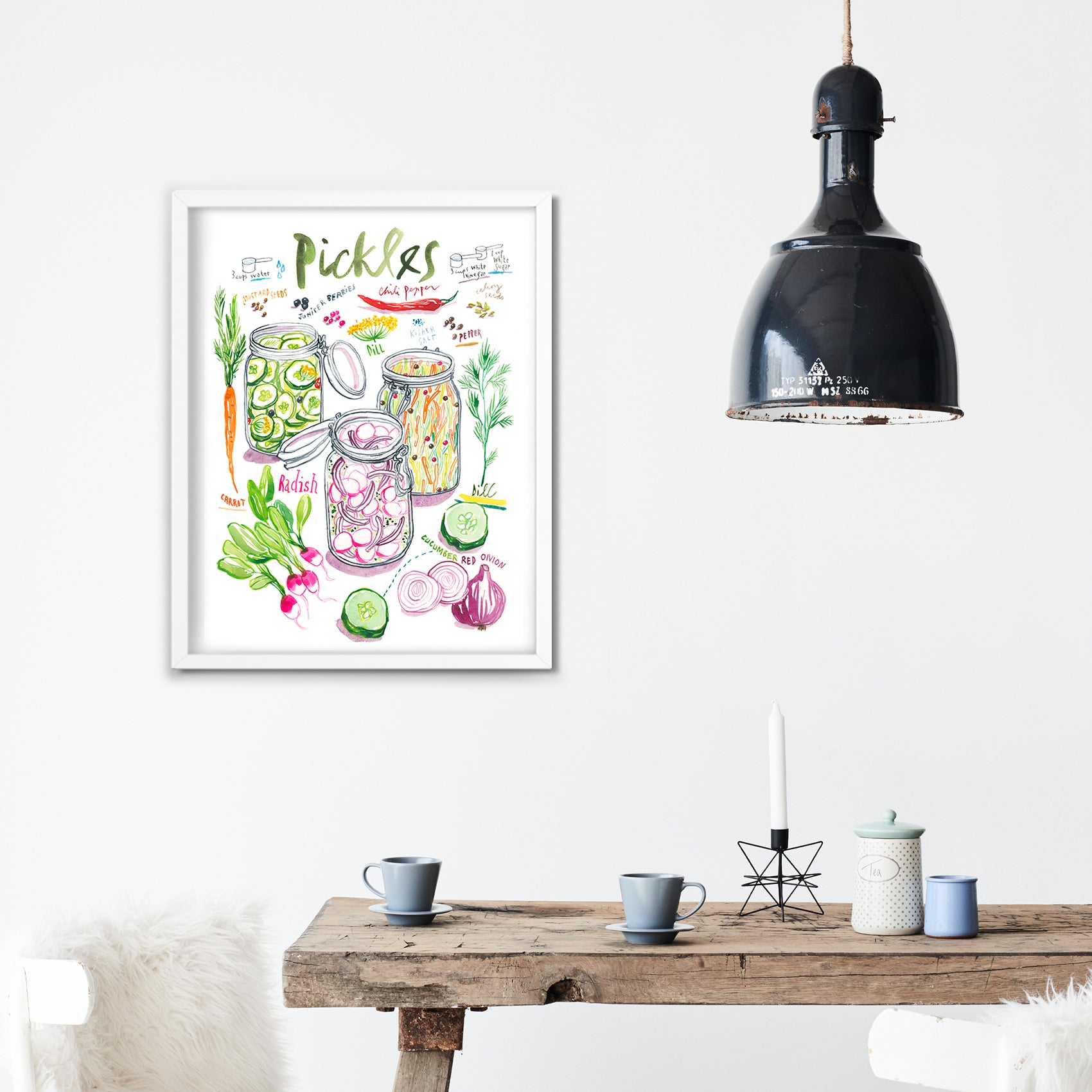 pickled vegetables recipe fine art print in watercolor featuring the ingredients and three jars of mixed veggies, along with handwritten instructions in English. The framed poster hanging in a dining space.
