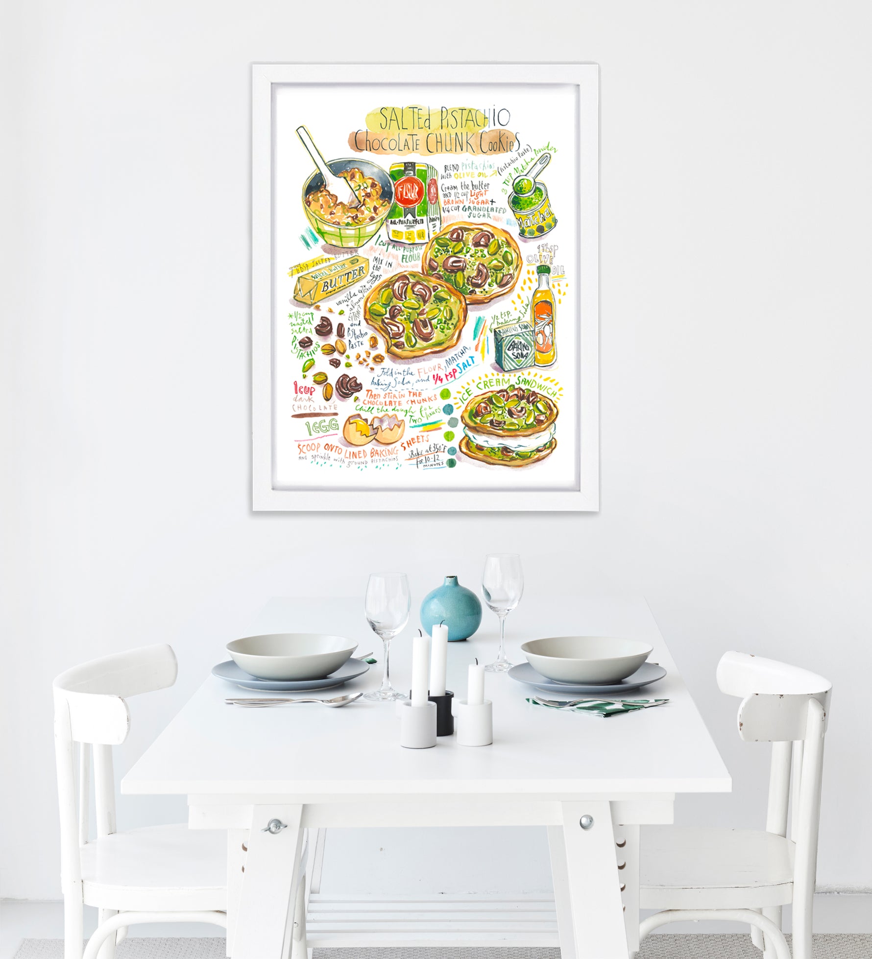 Salted pistachio chocolate chunk cookies recipe fine art print in watercolor featuring the ingredients and two cookies, along with handwritten instructions in English. The framed poster hanging in a dining space.