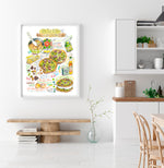 Salted pistachio chocolate chunk cookies recipe fine art print in watercolor featuring the ingredients and two cookies, along with handwritten instructions in English. The framed poster hanging in a dining space.