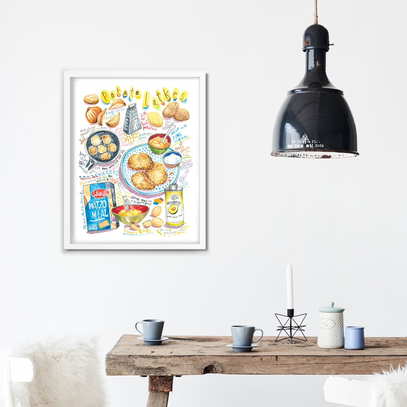 potato latkes recipe fine art print in watercolor featuring the ingredients and the finished dish, along with handwritten instructions in English. The framed poster hanging in a dining space.
