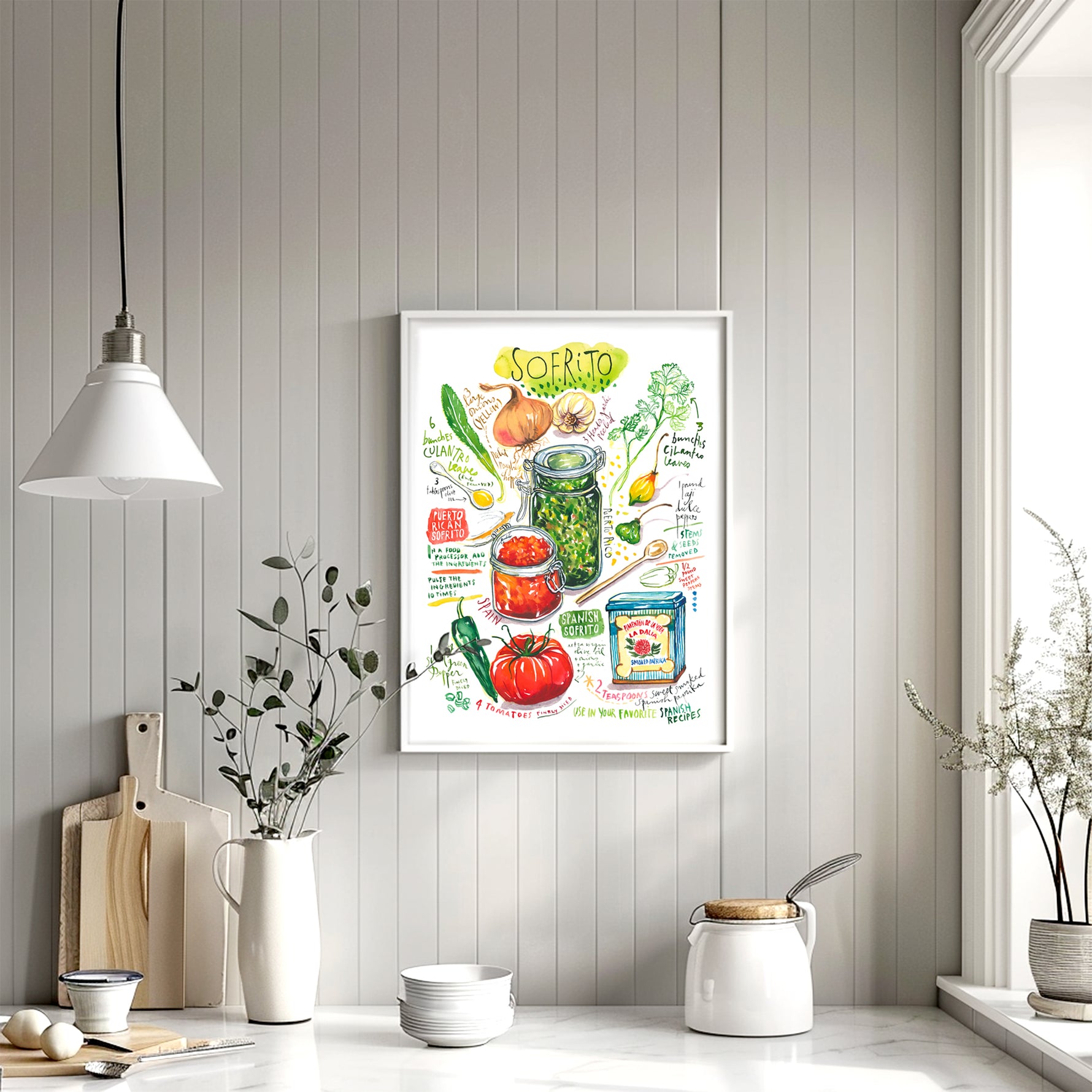 Spanish and Puerto Rican sofrito recipe fine art print in watercolor featuring the ingredients and the finished dish, along with handwritten instructions in English. The framed poster hanging in a dining space.