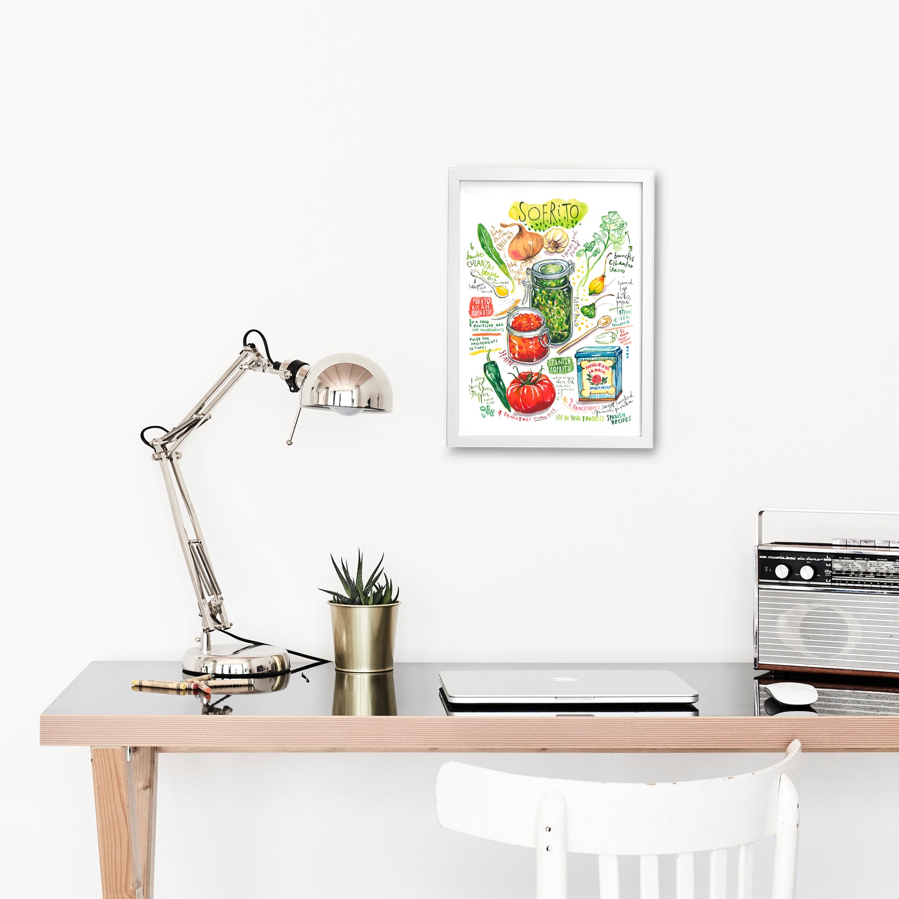 Spanish and Puerto Rican sofrito recipe fine art print in watercolor featuring the ingredients and the finished dish, along with handwritten instructions in English. The framed poster hanging in a working space.